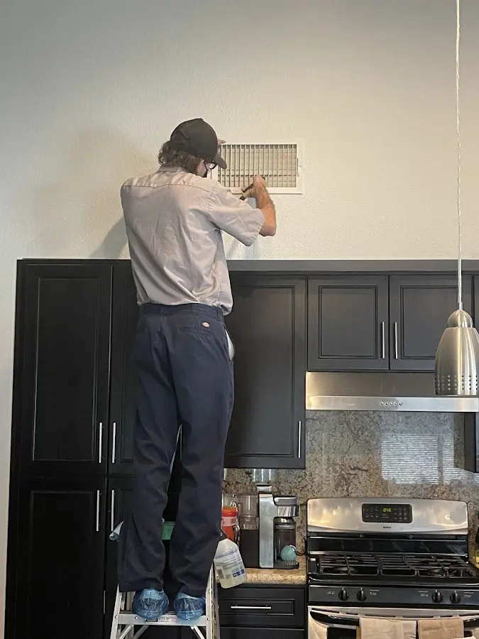 Technician inspecting an air vent during HVAC service in McFarland